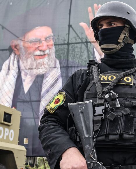 A member of the Iranian security forces stands guard next to a banner honoring Iran's slain supreme leader, Ayatollah Ali Khamenei, in Tehran on March 31, 2026. 