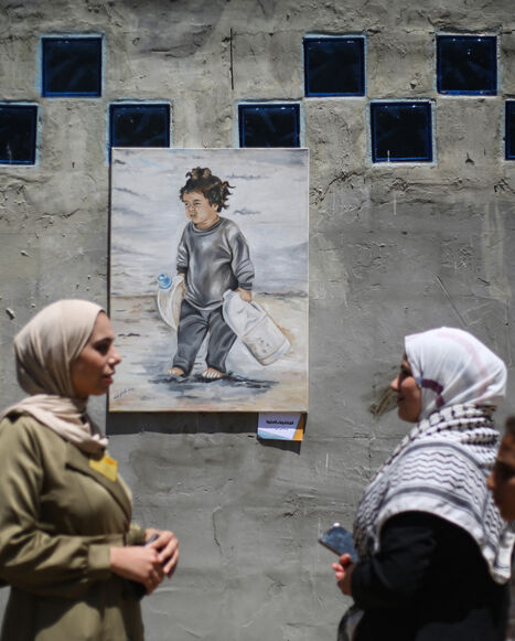 Displaced Palestinian people look at paintings at an open-air art exhibition at the Bureij camp for Palestinian refugees in the central Gaza Strip on April 28, 2026. The majority of Gaza's 2.4 million people have been displaced, often multiple times, by the war that began with Hamas's attack on southern Israel on October 7, 2023. With displaced families living in tented camps, with serious concerns raised about their living conditions. (Photo by Eyad Baba / AFP via Getty Images) / -- IMAGE RESTRICTED TO EDI