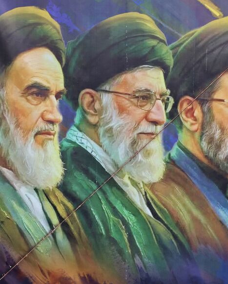A woman walks past a banner featuring Iran's late supreme leaders, Ayatollah Ruhollah Khomeini (L) and Ayatollah Ali Khamenei (C), next to newly elected Supreme Leader Ayatollah Mojtaba Khamenei, in Tehran on April 19, 2026. 