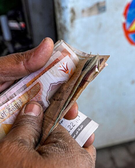 A worker counts banknotes after filling up the tank of a vehicle at a petrol station in Giza on March 10, 2026.