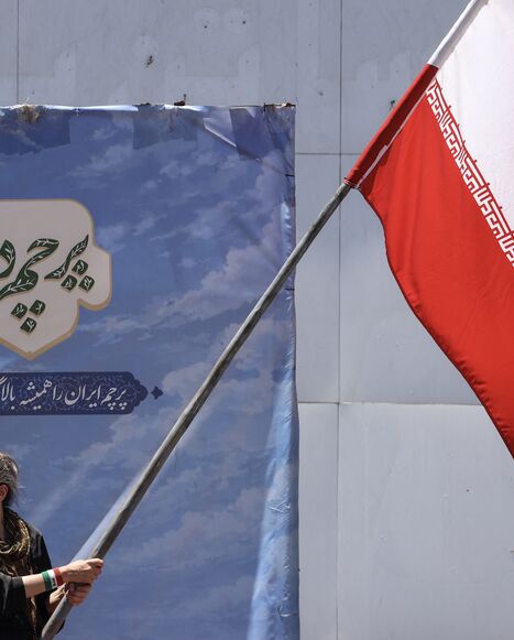 An Iranian woman waves a national flag at Valiasr Square in Tehran on June 15, 2026. 