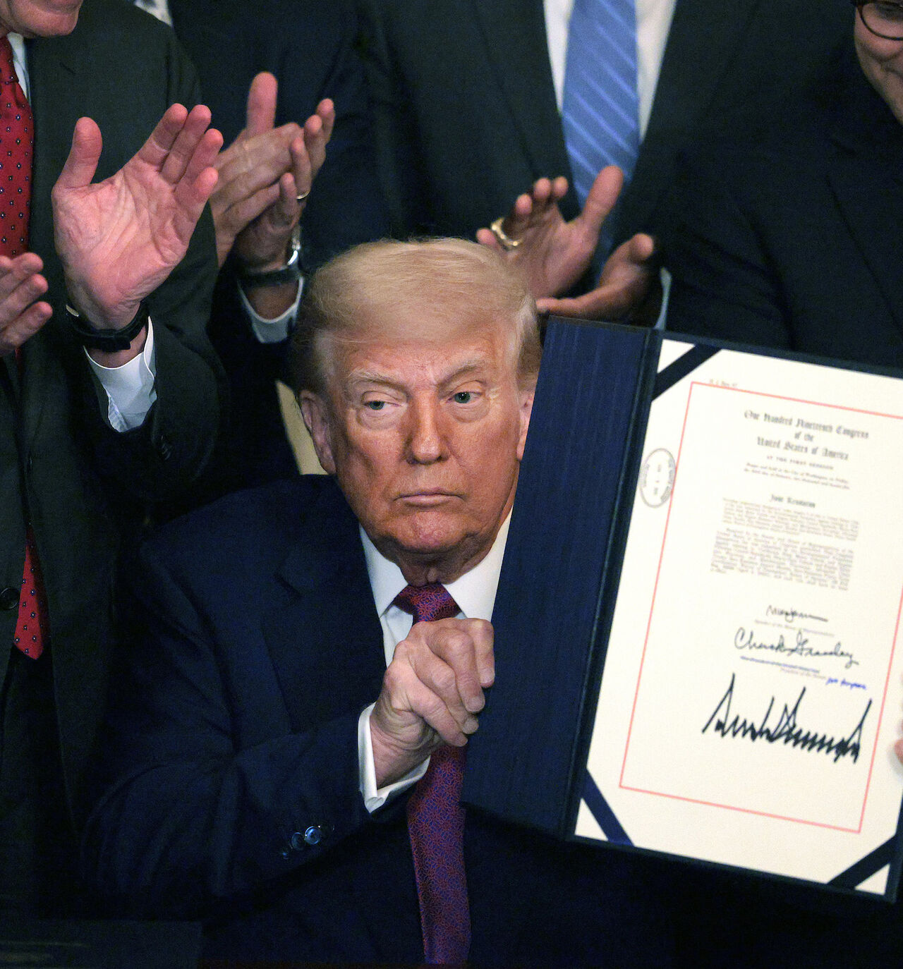 President Donald Trump, joined by Sen. John Barrasso (R-WY), Speaker of the House Mike Johnson (R-LA) and other lawmakers, holds up an executive order after signing a series of bills related to California’s vehicle emissions standards during an event in the East Room of the White House on June 12, 2025 in Washington, DC.