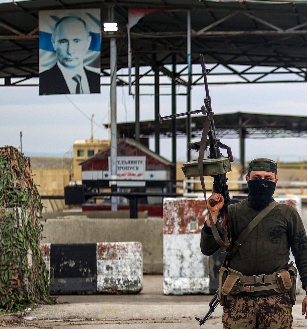 A Syrian rebel fighter looks on as he stands at an inspection checkpoint for incoming vehicles at the entrance of the Russian-leased Syrian military base of Hmeimim in Latakia province in western Syria on Dec. 29, 2024. 
