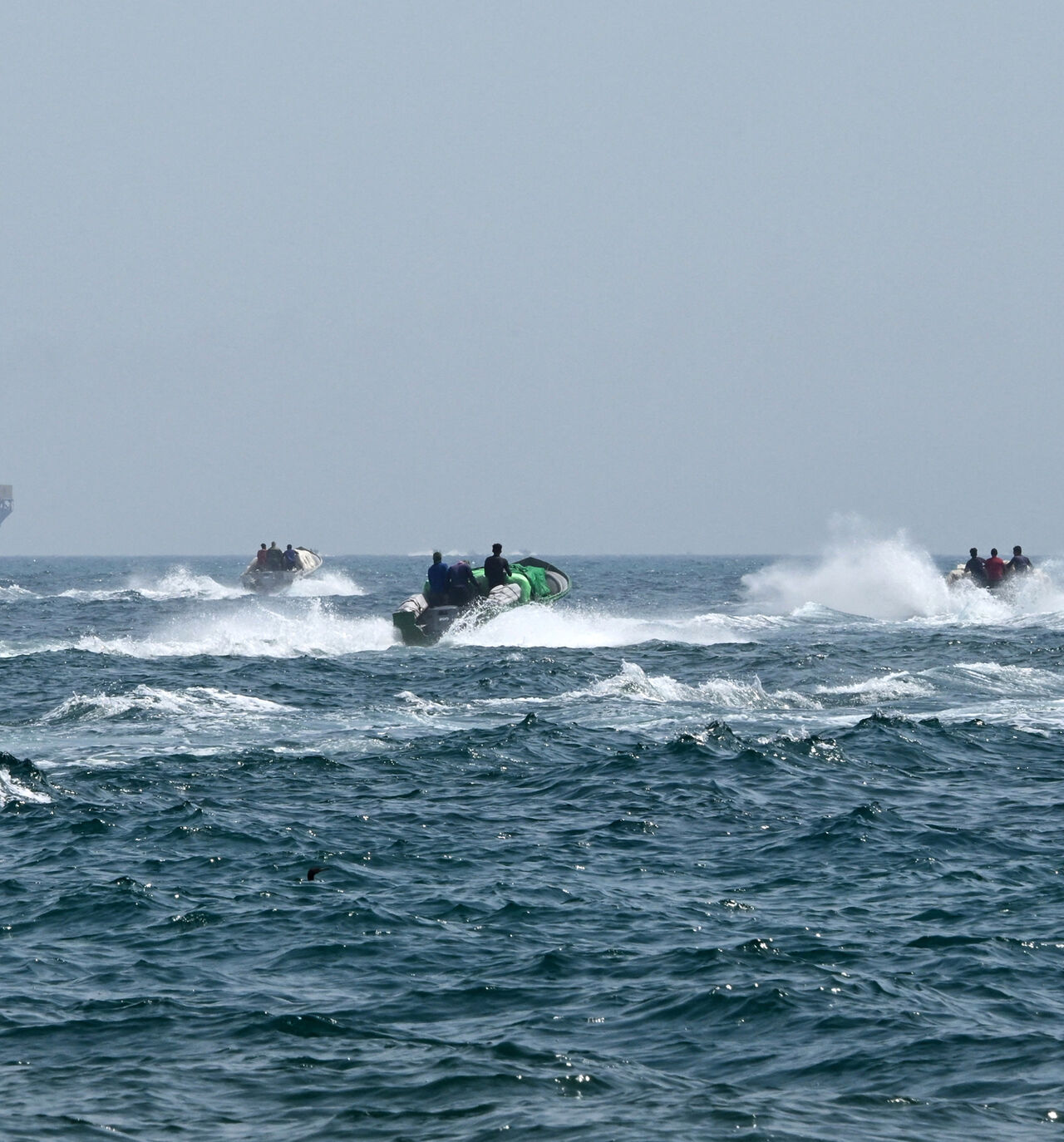 Small boats loaded with merchandise sail past the St Kitt's and Nevis-flagged container ship Marsa Victory in the waters of the Strait of Hormuz off the coast of Khasab in the northern Musandam Peninsula, Oman, June 25, 2025.