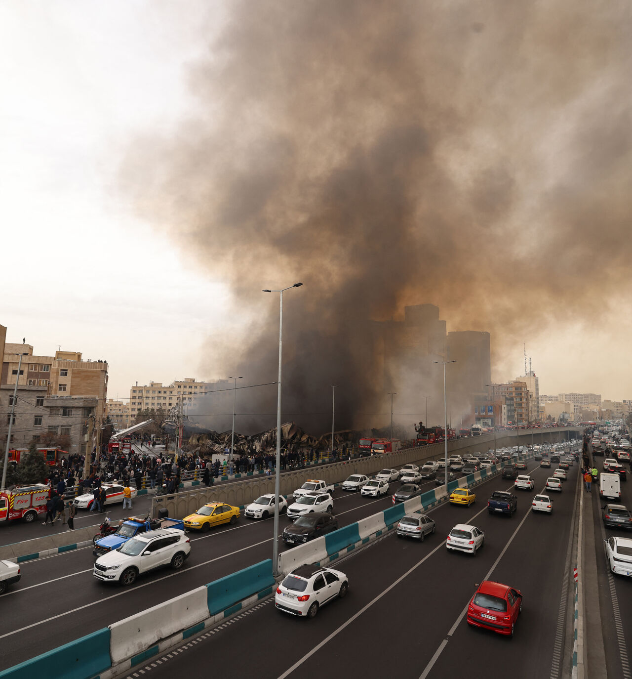 Motorists drive past as firefighters battle a fire that broke out in Jannat Bazaar, west of Tehran on Feb. 3, 2026. 