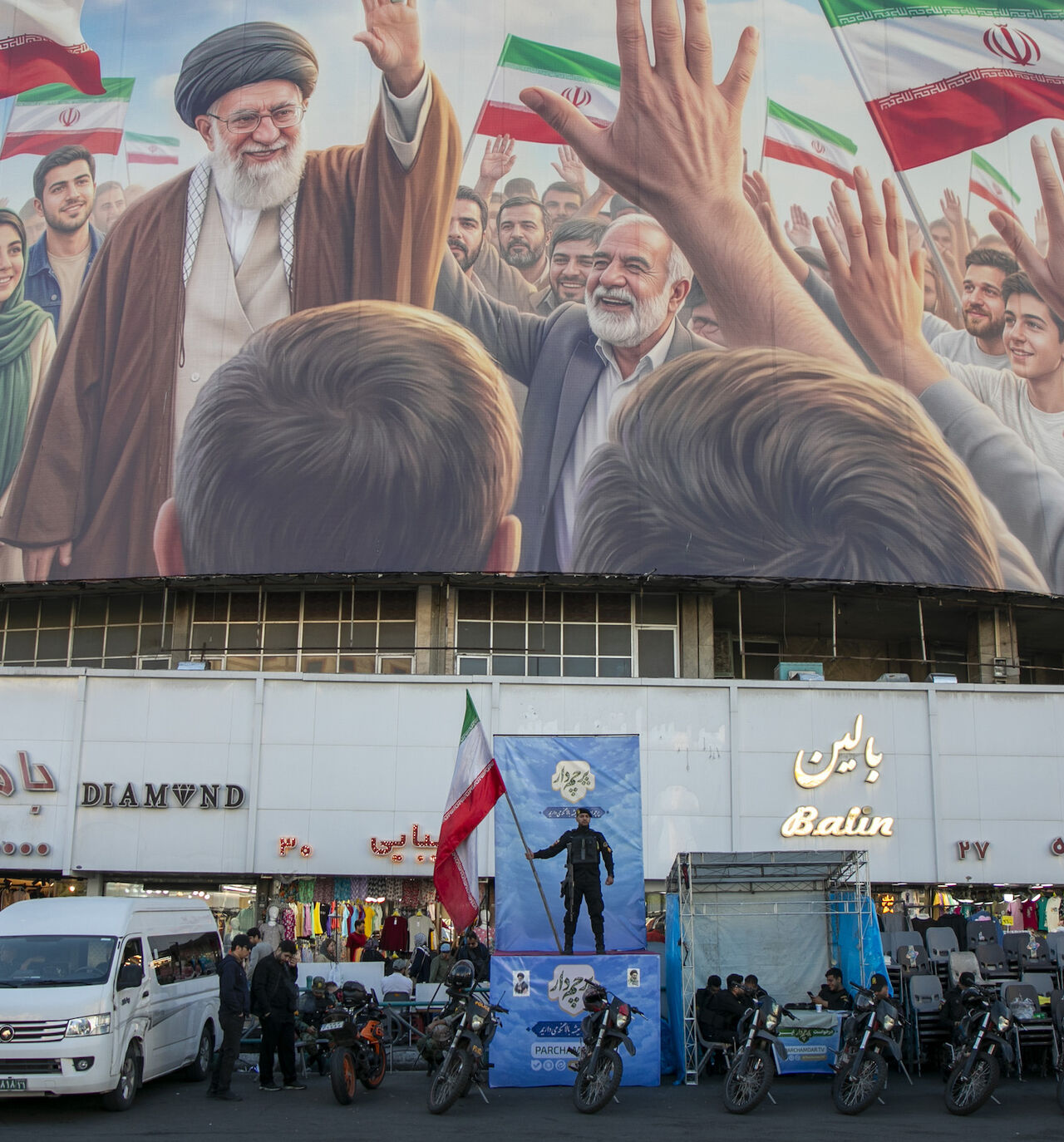 A police officer stands holding a flag in Valiasr Square beneath a mural of the late Ayatollah Ali Khamenei on April 23, 2026 in Tehran, Iran. 