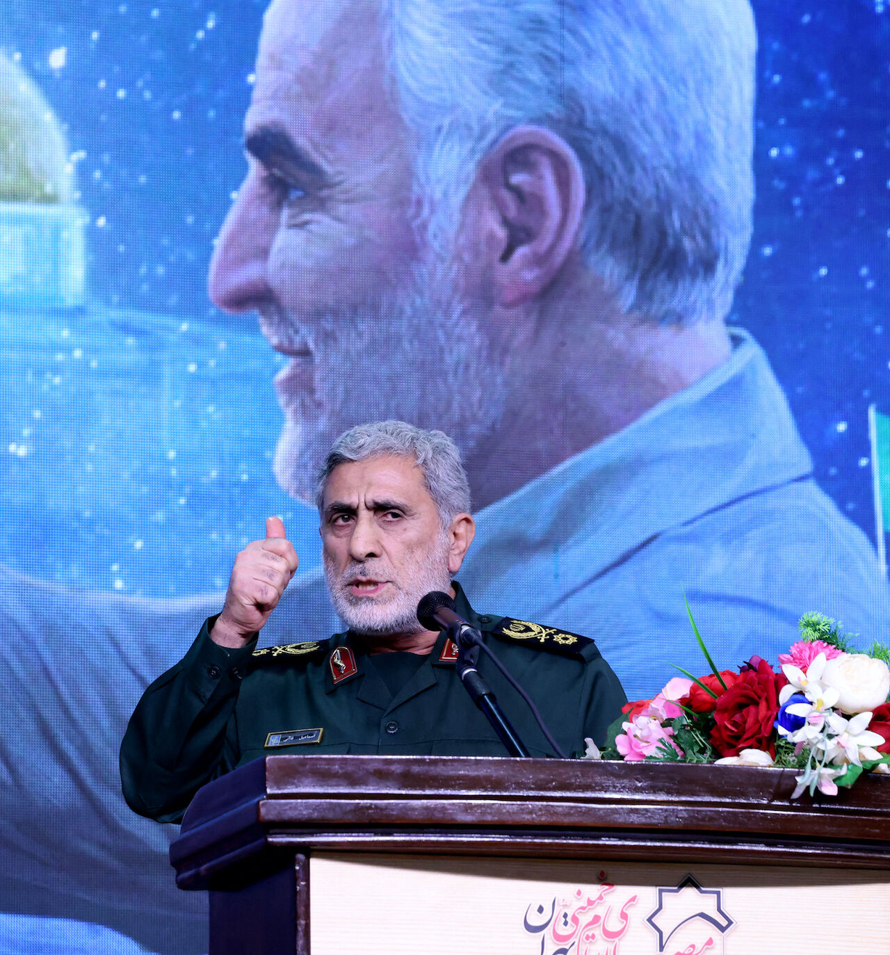 The commander of the Quds Force of the Islamic Revolutionary Guard Corps, Esmail Qaani, speaks during a commemoration ceremony marking the anniversary of the 2020 killing of Guards general Qasem Soleimani (on screen) in the capital Tehran on Jan. 3, 2024. 