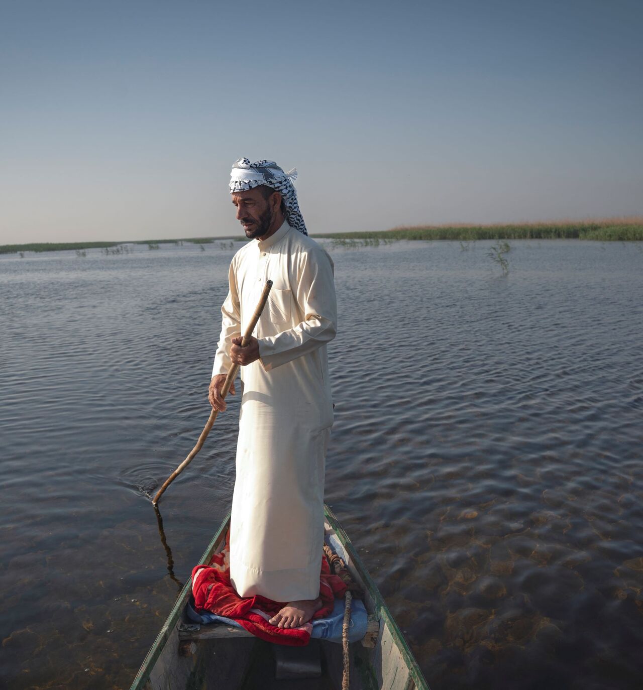 A man uses a pole to navigate a boat