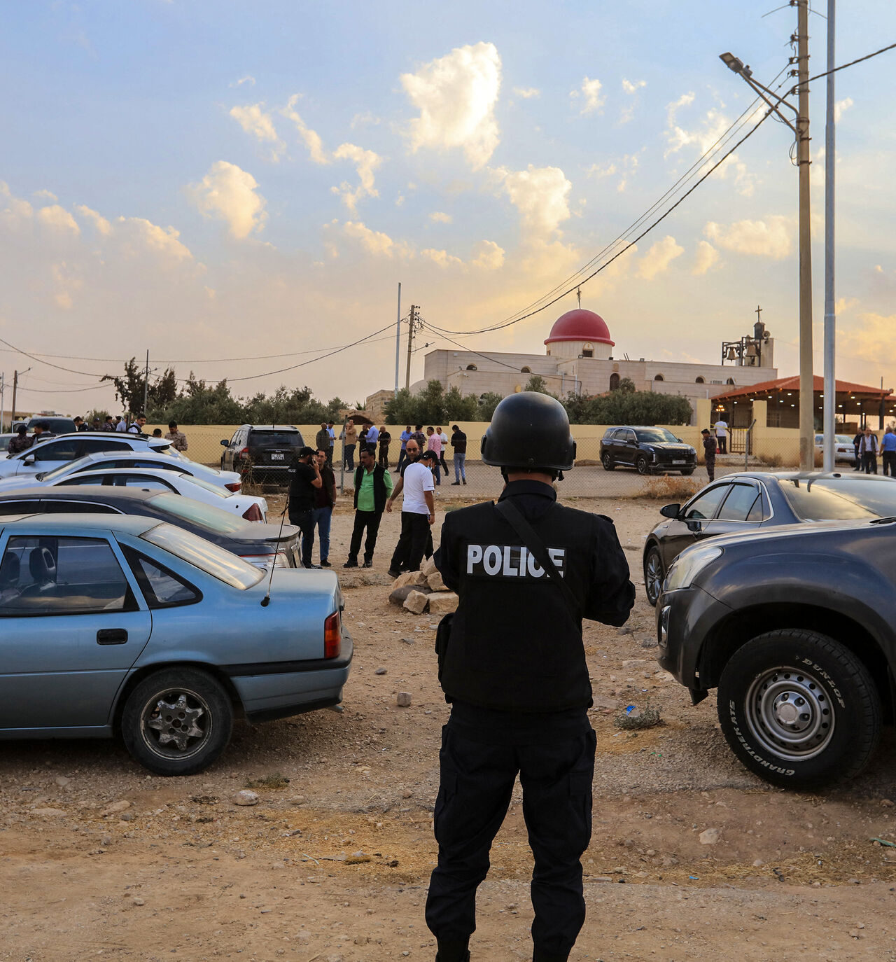 People and security forces gather outside a Greek Orthodox Church in the village of Hammoud in Jordan's Karak governorate following a shooting on October 23, 2026. 