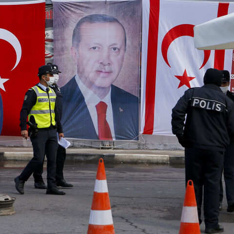 Turkish Cypriot police stand before a portrait of Turkish President Recep Tayyip Erdogan in the disputal coastal town of Varosha, in Famagusta, Cyprus, Nov. 15, 2020.