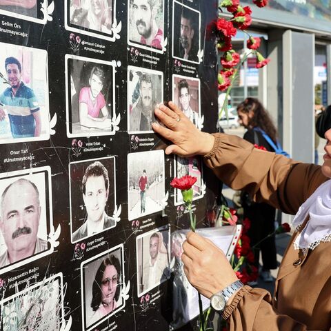 A woman holding a flower touches the picture of a suicide attack victim.