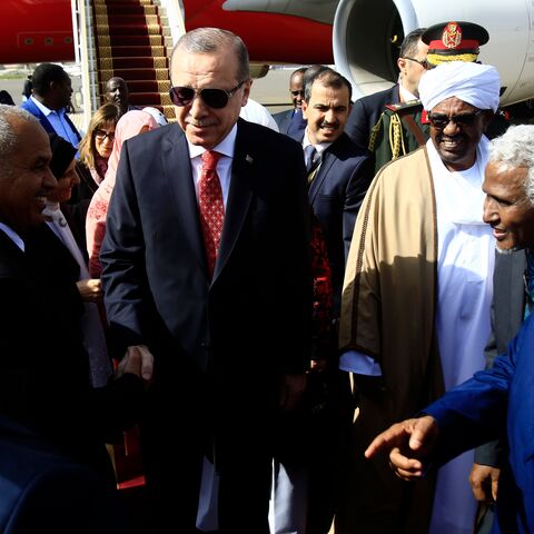 Turkish President Recep Tayyip Erdogan (C) is welcomed by his Sudanese counterpart Omar al-Bashir (2nd-L) and diplomats upon his arrival in Khartoum on December 24, 2017, for a two-day-official visit. / AFP PHOTO / ASHRAF SHAZLY (Photo credit should read ASHRAF SHAZLY/AFP via Getty Images)