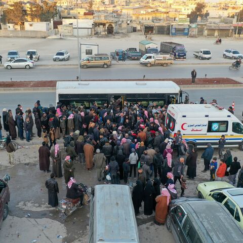 An aerial picture shows Syrian refugees living in Turkey waiting to take a bus through the northern Bab al-Hawa border crossing, on February 17, 2023, as they return to Syria in the aftermath of a deadly earthquake. - Turkey this week allowed Syrians under its protection who hold ID cards from one of the quake-hit provinces to leave for between three and six months, a rule change designed to reunite families on both sides of the border hit by the February 6 disaster, which has killed more than 41,000 people