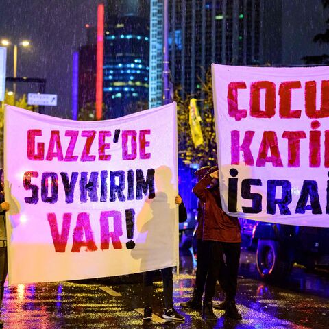 Turkish football supporters hold banners reading "There is a genocide in Gaza" and "Children killer Israel" during a demonstration to demand a stop to the bombings in Gaza in front of the Israeli consulate in Istanbul, on November 18, 2023 amid ongoing battles between Israel and the Palestinian Hamas movement in the Gaza Strip. (Photo by YASIN AKGUL / AFP) (Photo by YASIN AKGUL/AFP via Getty Images)