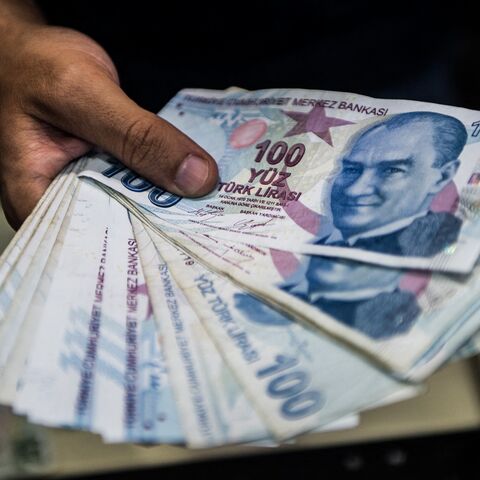 A teller holds Turkish lira banknotes at a currency exchange office in Istanbul, Aug. 13, 2018.