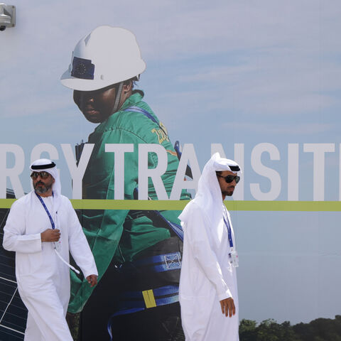 Men wearing thawbs walk past a billboard promoting the transition to renewable energies at the UNFCCC COP28 Climate Conference the day before its official opening on November 29, 2023 in Dubai, United Arab Emirates. The COP28 is bringing together stakeholders, including international heads of state and other leaders, scientists, environmentalists, indigenous peoples representatives, activists and others to discuss and agree on the implementation of global measures towards mitigating the effects of climate c