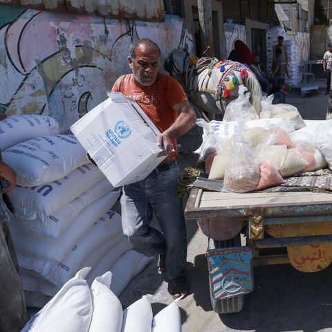 Palestinians carry bags of flour provided as aid to poor families at the United Nations Relief and Works Agency for Palestine Refugees (UNRWA) distribution center, in the Al-Shati refugee camp in Gaza city on June 5, 2023.