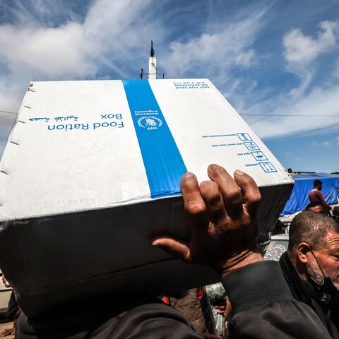 Displaced Palestinians carry a box of food rations provided by the World Food Program at a makeshift street market in Rafah in the southern Gaza Strip on March 14, 2024, amid ongoing battles between Israel and the militant group Hamas. 