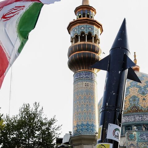 Iranians lift up a flag and the mock up of a missile during a celebration following Iran's missiles and drones attack on Israel, on April 15 2024, at Palestine square in central Tehran.