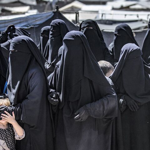 Women and a child queue to receive humanitarian aid packages at the Kurdish-run al-Hol camp.