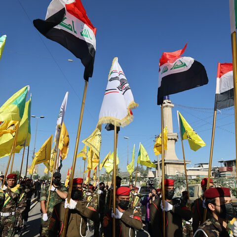 Fighters lift flags of Iraq and paramilitary groups, including al-Nujaba and Kataib Hezbollah, during a funeral in Baghdad for five militants killed a day earlier in a US strike in northern Iraq, on December 4, 2023. 