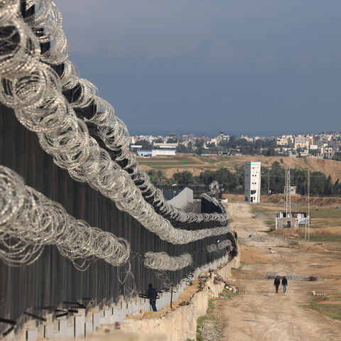 Displaced Palestinians walk next to the border fence between Gaza and Egypt, on February 16, 2024 in Rafah, in the southern Gaza Strip, amid the ongoing conflict between Israel and the Palestinian Hamas militant group. Nearly 1.5 million displaced Palestinians are trapped in Rafah -- more than half of Gaza's populations -- seeking shelter in a sprawling makeshift encampment near the Egyptian border. (Photo by MOHAMMED ABED / AFP) (Photo by MOHAMMED ABED/AFP via Getty Images)