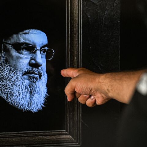 A man points to a television set displaying an image of the late leader of Hezbollah, Hassan Nasrallah.