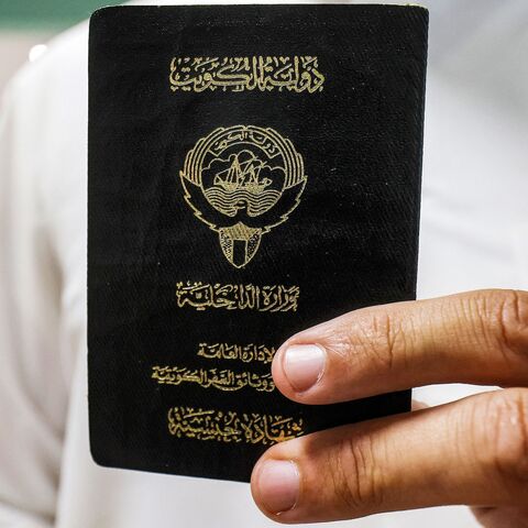 A voter holds his proof of Kuwaiti citizenship upon arriving at a polling station during parliamentary elections in Kuwait City on June 6, 2023. 