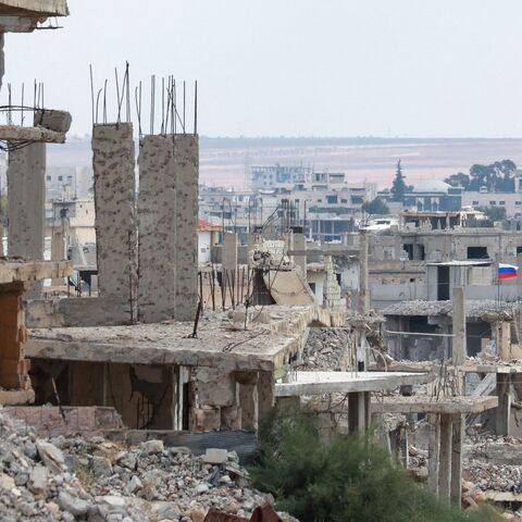 A picture taken during a tour organized by the Syrian Ministry of Information shows flags of Russia and Syria atop a damaged building in the district of Daraa al-Balad of Syria's southern city of Daraa, on Sept. 12, 2021.