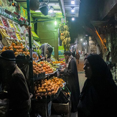 People walk past a fruit seller's stall in the Azhar district of Egypt's capital, Cairo, on Jan. 16, 2023.