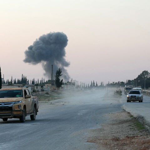 Anti-regime fighters drive along the Aleppo- Damascus M5 international highway in the newly captured northwestern area of Khan al-Assal, as smoke rises in the distance on Nov. 29, 2024. 