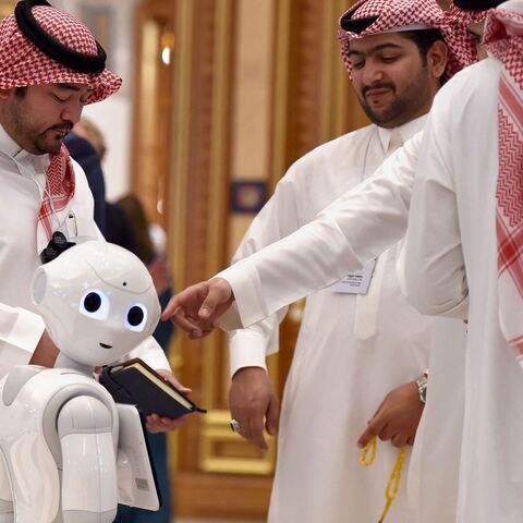 Delegates chat near a robot during the Future Investment Initiative (FII) forum at the King Abdulaziz Conference Centre in Saudi Arabia's capital Riyadh, on Oct. 30, 2019. 