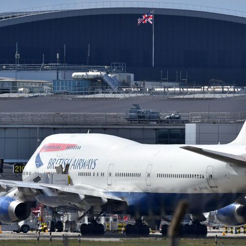 A Union flag flies above a hangar as a British Airways operated Airbus A747 passenger jet is moved by an aircraft tractor at Heathrow Airport, west of London on April 2, 2020, as life in Britain continues during the nationwide lockdown to combat the novel coronavirus COVID-19 pandemic. 