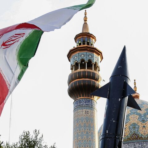 Iranians lift up a flag and the mock up of a missile during a celebration following Iran's missiles and drones attack on Israel, on April 15, 2024, at Palestine square in central Tehran.