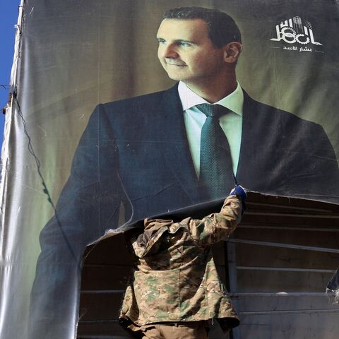 An anti-government fighter tears down a portrait of Syria's President Bashar al-Assad in Aleppo, after jihadis and their allies entered the northern Syrian city, on Nov. 30, 2024. 