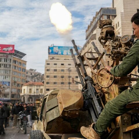 A Syrian rebel fighter fires rounds as people celebrate near the New Clock Tower in the central city of Homs on Dec. 8, 2024. 