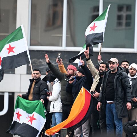 Members of the Syrian community in Berlin hold flags of Syria and Germany as they celebrate the collapse of Syrian President Bashar al-Assad's government, Dec. 8, 2024.