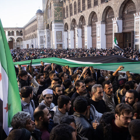 People chant slogans and wave flags in celebration after performing the first Friday prayer since the fall of the Assad regime at the Umayyad Mosque on Dec. 13, 2024 in Damascus, Syria. 