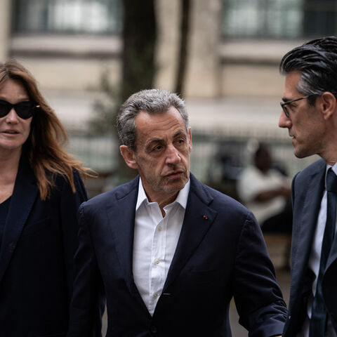 French former president Nicolas Sarkozy (C) and his wife Carla Bruni-Sarkozy arrive to vote for the first round of parliamentary elections in Paris, on June 30, 2024. A divided France is voting in high-stakes parliamentary elections that could see the anti-immigrant and eurosceptic party of Marine Le Pen sweep to power in a historic first. The candidates formally ended their frantic campaigns at midnight June 28, with political activity banned until the first round of voting. (Photo by ARNAUD FINISTRE / AFP