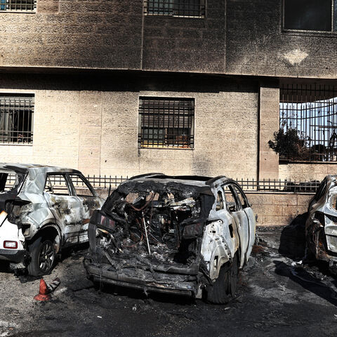 A man stands by burnt vehicles at the site of a reported attack by Israeli settlers in a residential area on the outskirts of Ramallah city in the occupied West Bank, on November 4, 2024. (Photo by Zain JAAFAR / AFP) (Photo by ZAIN JAAFAR/AFP via Getty Images)