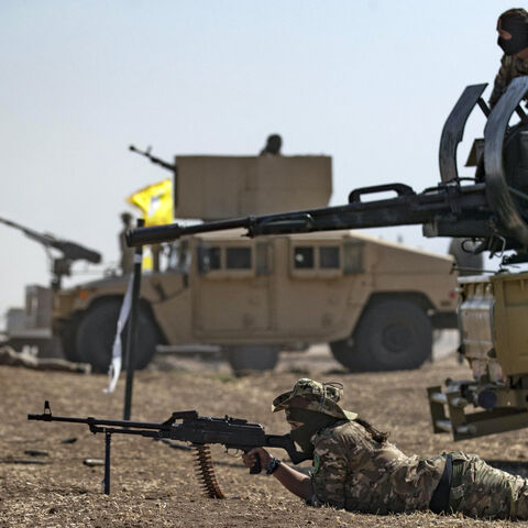 A fighter of the Syrian Democratic Forces (SDF) aims a machine gun while lying prone during a joint military exercise with forces of the US-led "Combined Joint Task Force-Operation Inherent Resolve" coalition against the Islamic State (IS) group in the countryside of the town of al-Malikiya (Derik in Kurdish) in Syria's northeastern Hasakah province on Sept. 7, 2022. 