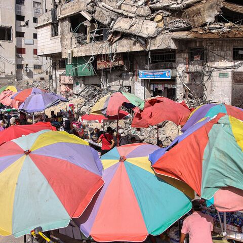 Vendors' umbrellas shade their stalls while erected before destroyed buildings along a market street in Gaza City, June 15, 2024. 