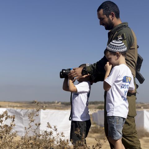 Israeli soldier and kids use binoculars during a Sukkoth gathering, calling for resettling Gaza with Jewish communities near the border with the Gaza Strip on Oct. 21, 2024 in Southern Border, Israel. 