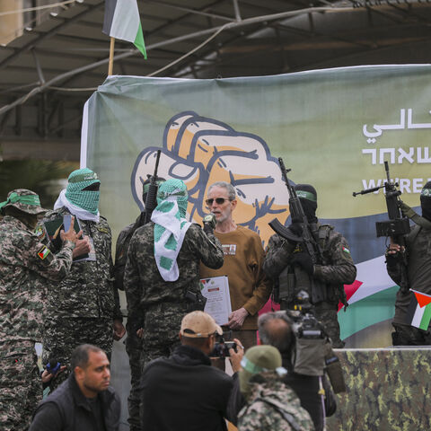 Israeli hostages stand on stage flanked by Hamas militants during the official handover in Gaza, Gaza Strip, on February 8, 2025. Hamas hands over three Israeli hostages to the Red Cross as part of ongoing negotiations. (Photo by Youssef Alzanoun / Middle East Images / Middle East Images via AFP) (Photo by YOUSSEF ALZANOUN/Middle East Images/AFP via Getty Images)