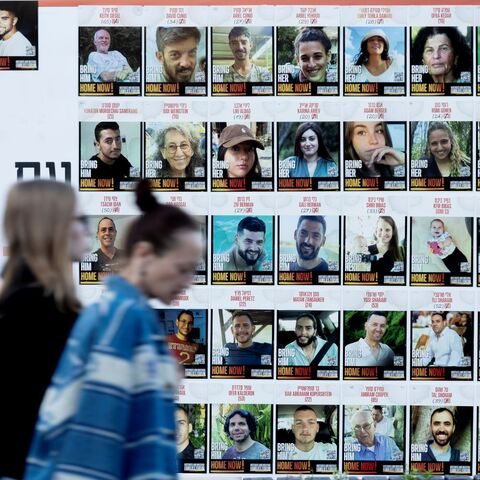 Women pass by a wall covered with photos of hostages that were kidnaped to the Gaza Strip during Hamas deadly attack on Jan. 6, 2025 in Kfar Saba, Israel.