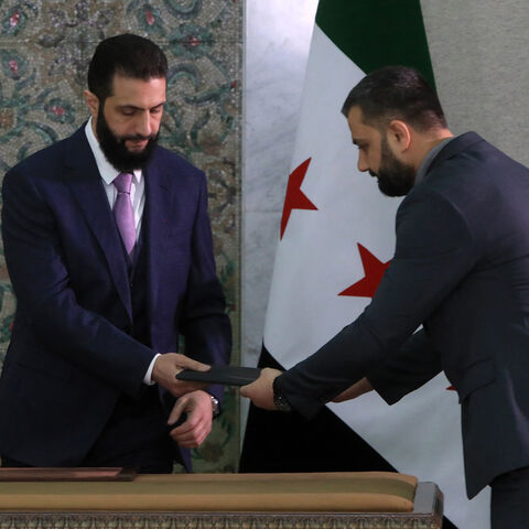 Syria's interim President Ahmad al-Sharaa receives the country's constitutional declaration, which will be enforced throughout a five-year transitional period, before signing it at the presidential palace in Damascus on March 13, 2025. Sharaa said he hoped the constitutional declaration would mark the start of "a new history for Syria, where we replace oppression with justice", as he signed the document setting out the transitional period. (Photo by Bakr ALKASEM / AFP) (Photo by BAKR ALKASEM/AFP via Getty I