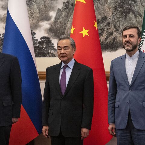 China's Foreign Minister Wang Yi (C) welcomes Russia's deputy foreign minister, Sergey Ryabkov (L), and Iran's deputy foreign minister, Kazeem Gharibabadi, before a meeting regarding the Iranian nuclear issue on March 14, 2025.