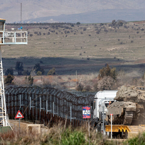An Israeli army Merkava main battle tank is carried on the back of a trailer truck to be deployed near a watchtower of the UN-patrolled buffer zone's Quneitra checkpoint, separating Israeli and Syrian forces in the Golan Heights, on March 2, 2025. (Photo by Jalaa MAREY / AFP) (Photo by JALAA MAREY/AFP via Getty Images)
