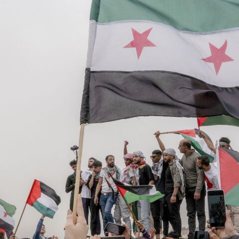 People wave the flag of Palestine and the new flag of Syria as Syrians gather in a protest dubbed "Syrians Against the Occupation" to denounce Israel's continued war on Gaza as well as its occupation of parts of Syria and Palestine in Damascus, Syria, on April 7, 2025.