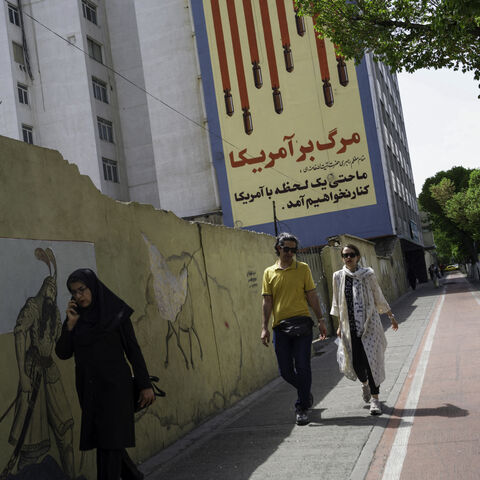 Iranians pass by the recently repainted, famous anti-American mural that depics the US flag with bombs and skulls in Tehran, Iran on April 10, 2025, two days before the first round of indirect nuclear negotiations with President Trump's administration hosted and mediated by Oman. (Photo by Mohammadali Najib / Middle East Images / Middle East Images via AFP) (Photo by MOHAMMADALI NAJIB/Middle East Images/AFP via Getty Images)